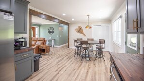 A spacious kitchen with a dining area, wooden flooring, and a coffee machine.