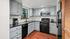 A modern kitchen with grey cabinets, a black stove, stainless steel appliances, and a wooden floor. - Sleeps 6 Indoor Pool 10 Mins to Dollywood (Pigeon Forge)