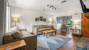 A living room with a sofa, coffee table, and lamps. There is a dining area with a table and chairs. - Sleeps 6 Indoor Pool 10 Mins to Dollywood (Pigeon Forge)