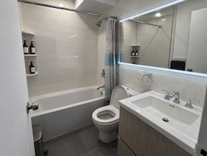 Een moderne badkamer met een bad, toilet en wastafel.
