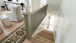 A staircase with a wooden floor and a railing, leading to a room with a large window and a painting on the wall. - The Portico - 2 BR 1 BA Apt (Griffin)