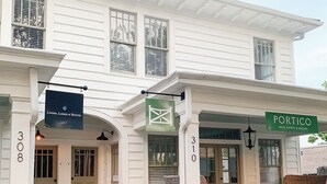 A white two-story building with a porch, numbered 310, featuring signs for 'Luderer, Larkin & Hunter' and 'Portico Real Estate & Design'. - The Portico - 2 BR 1 BA Apt (Griffin)