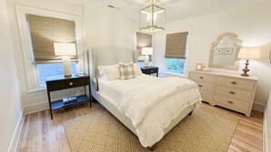 A bedroom with a bed, nightstands, a dresser, and a chandelier. - The Portico - 2 BR 1 BA Apt (Griffin)