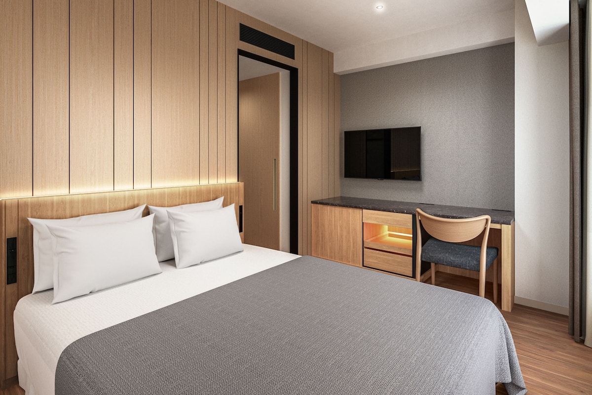 Une chambre d’hôtel moderne équipée d’un lit, d’un bureau, d’une chaise et d’un téléviseur.