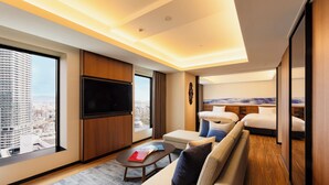 Una habitación de hotel moderna con un ventanal grande, un televisor de pantalla plana, un sofá y una mesita.