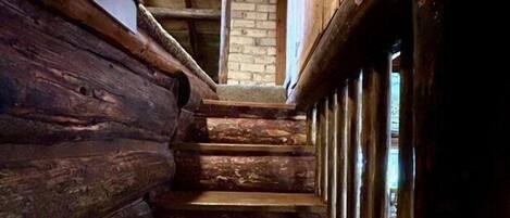 Una estrecha escalera de madera con una pared de ladrillo en la parte superior.