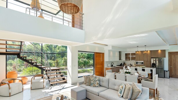 Un'ampia zona giorno con soffitto alto, una cucina e una scala che conduce a un livello superiore.