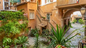 A narrow courtyard with a water feature, potted plants, and a staircase leading to an upper level. - Al Cortile del Moro Suite (Roma)