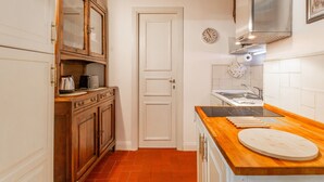 A kitchen with wooden cabinets, a stainless steel range hood, a wooden countertop, and a white door. - Al Cortile del Moro Suite (Roma)