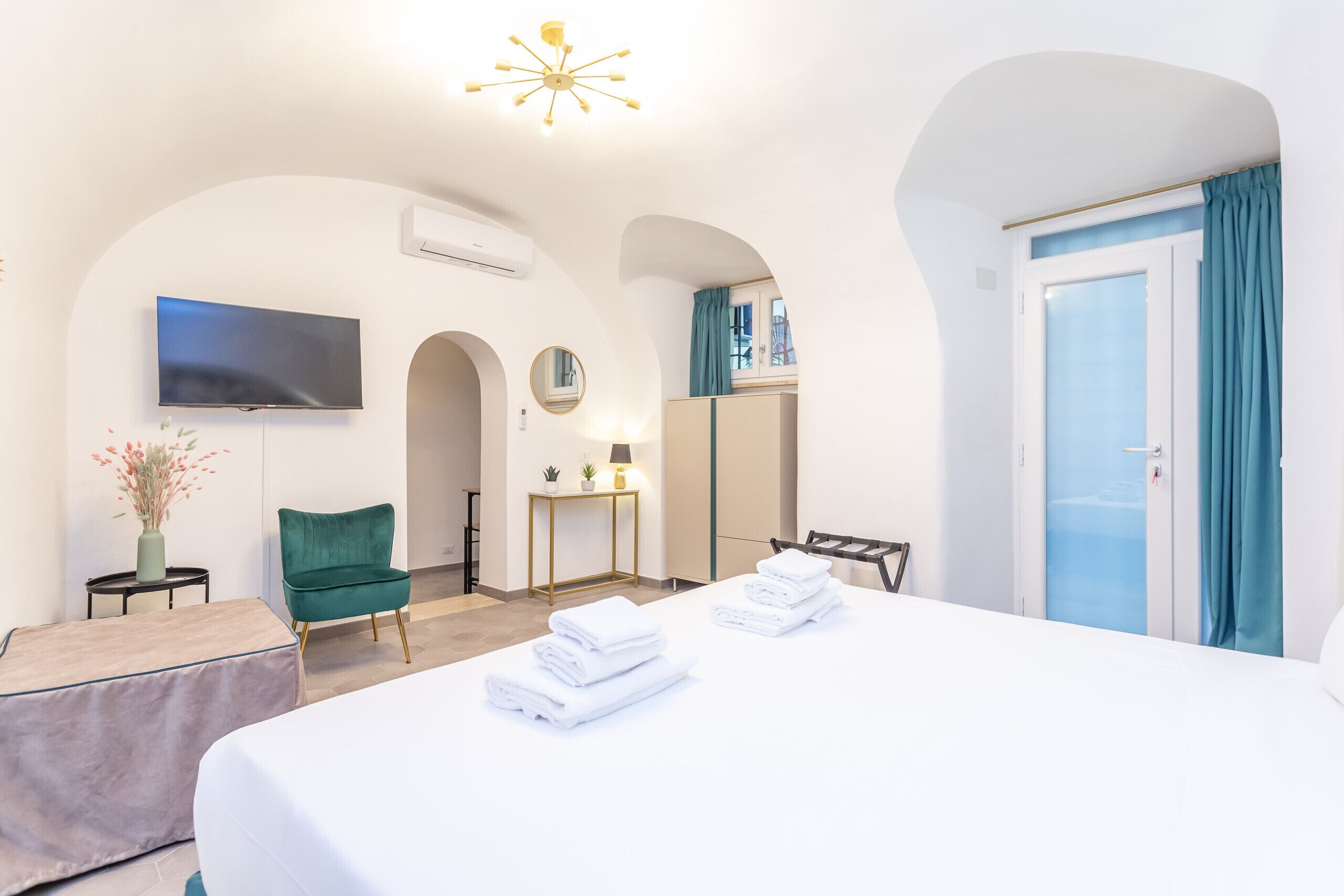 A hotel room with a bed, a TV, a desk, a chair, and a wardrobe.