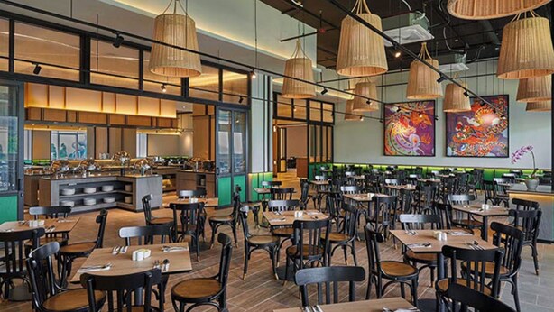 Een restaurant met meerdere eettafels, stoelen, een keuken en kunstwerken aan de muren.