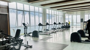 Een ruime fitnessruimte met diverse trainingsapparaten, grote ramen en een modern design.