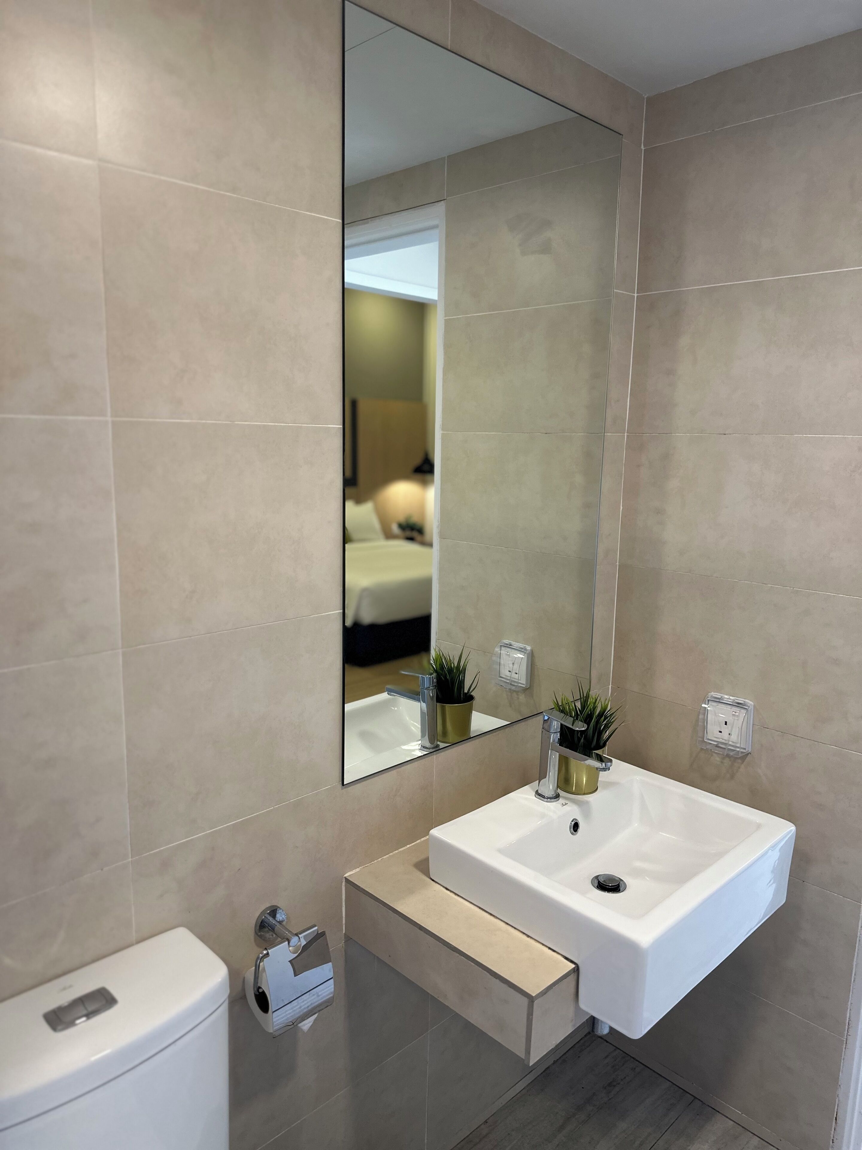 A modern bathroom with a large mirror, white sink, and a toilet.