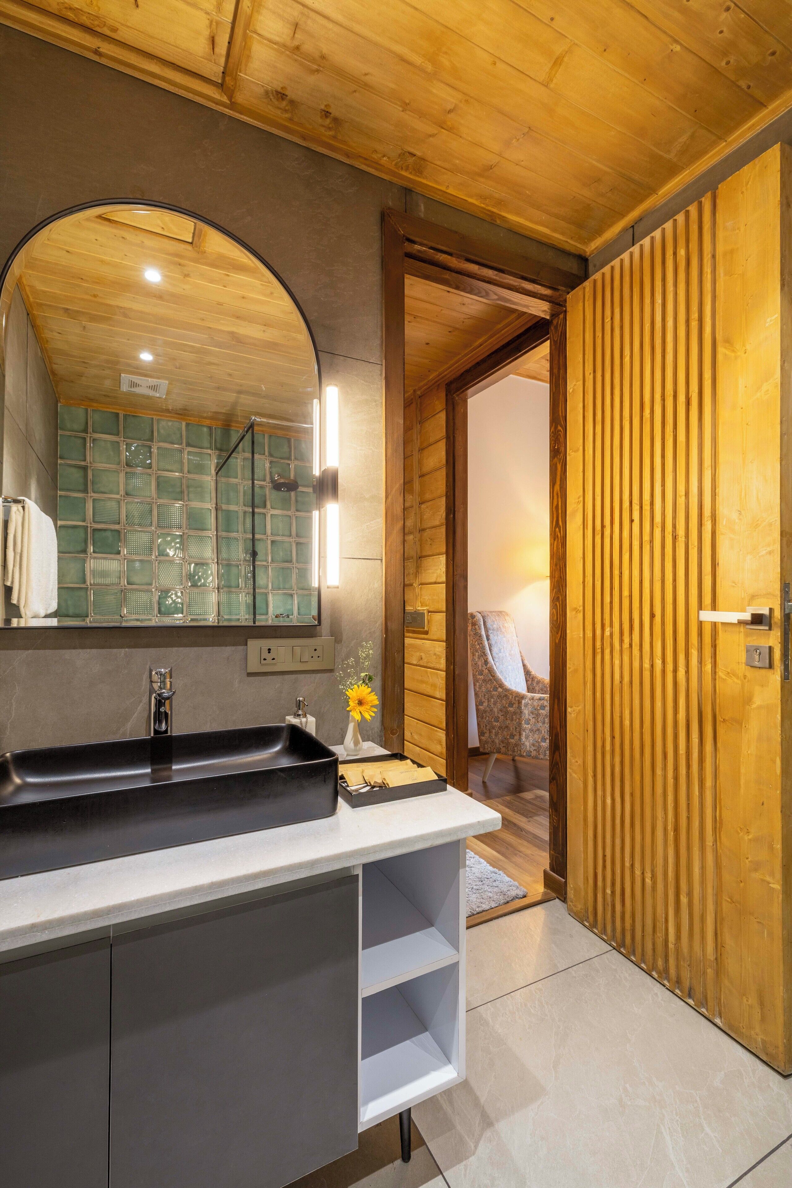 A bathroom with a wooden ceiling, a large mirror, a black sink, and a white vanity.