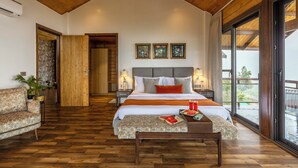 Une chambre spacieuse avec un grand lit, un plancher en bois, un balcon avec vue et un design moderne.