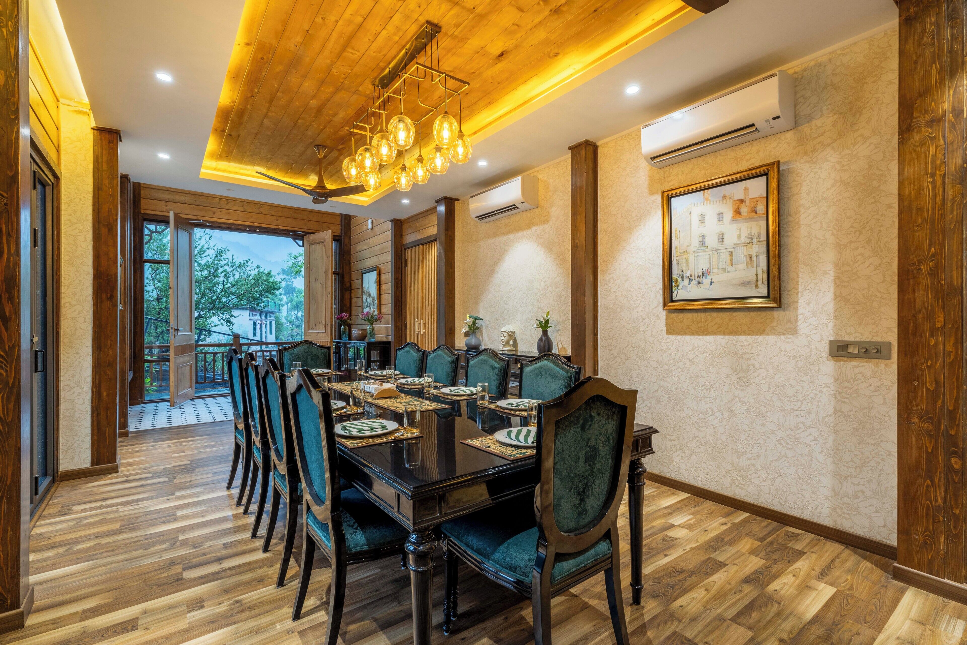 A dining area with a long wooden table set for six, surrounded by green upholstered chairs.