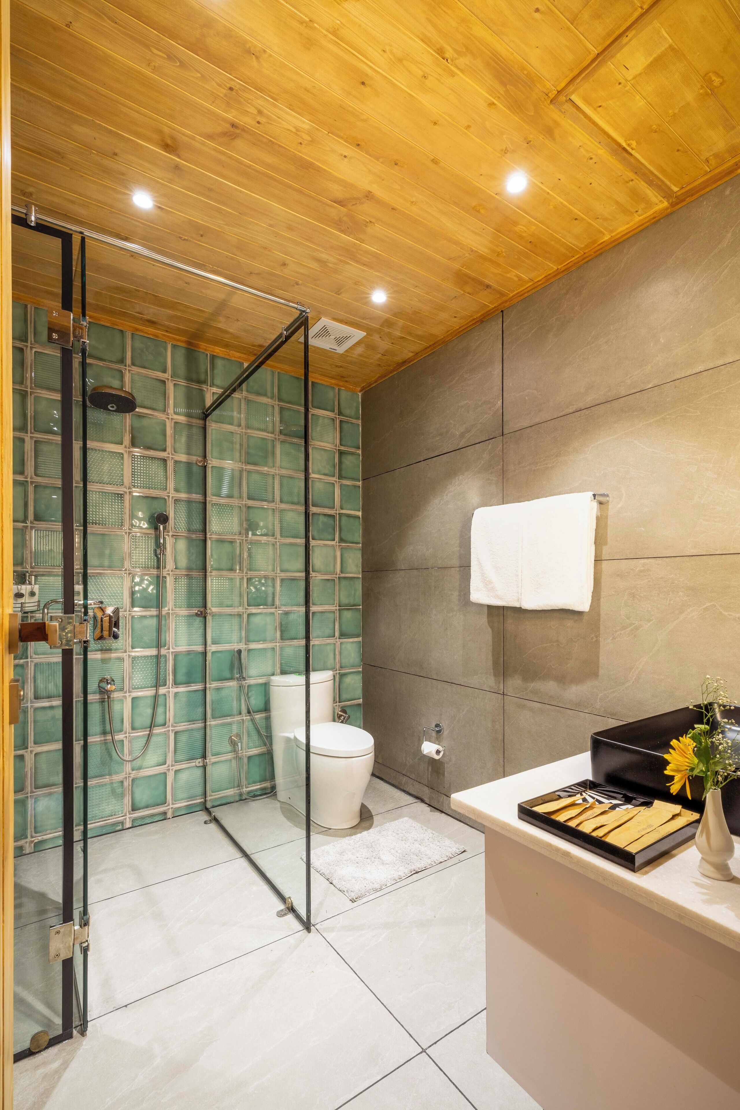 Une salle de bain moderne avec une douche à parois de verre, des toilettes et un meuble-lavabo doté d’un évier et d’un porte-serviettes.