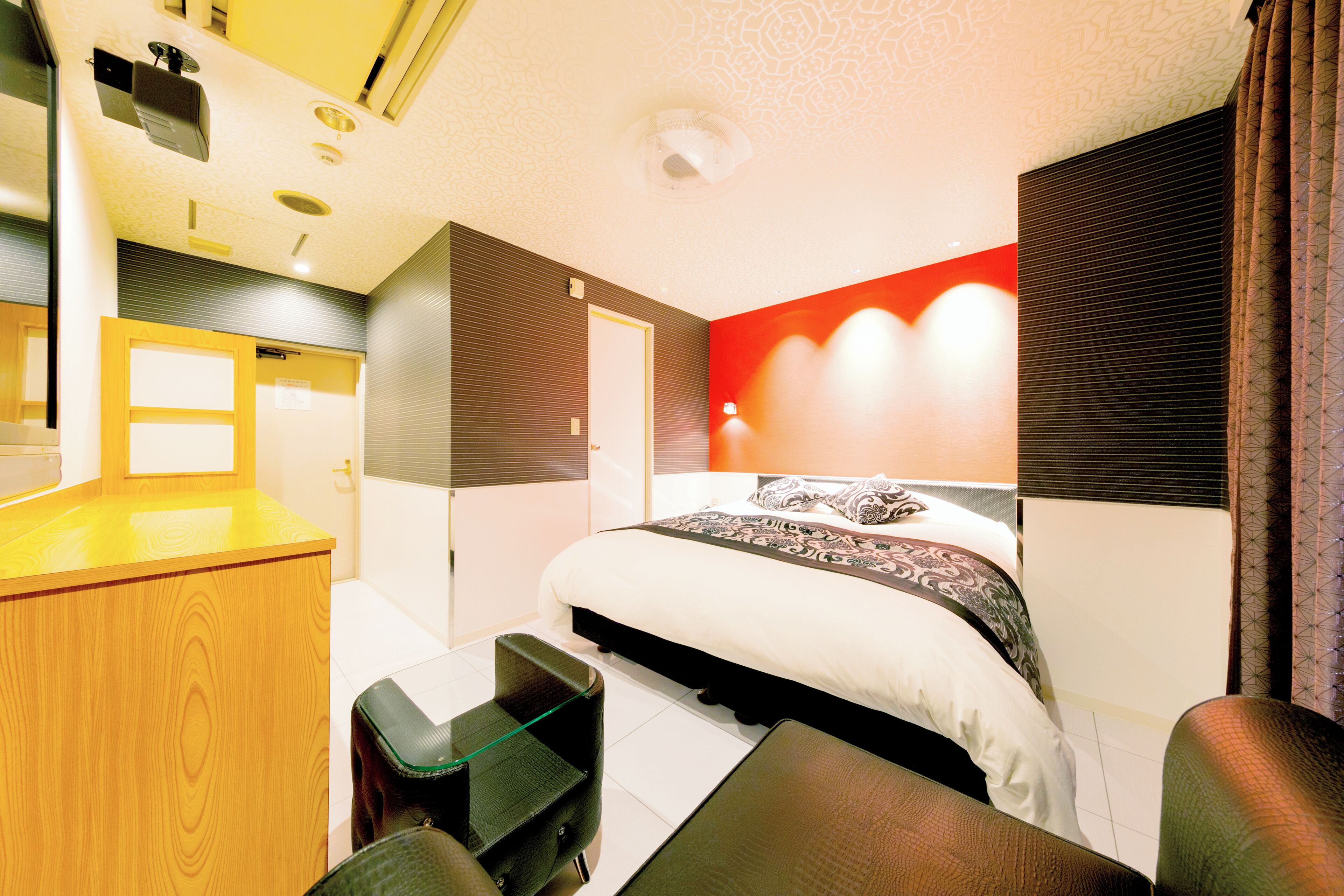 A modern hotel room with a bed, a desk, and a chair.
