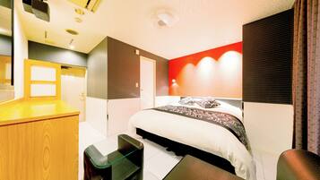 A modern hotel room with a bed, a desk, and a chair.
