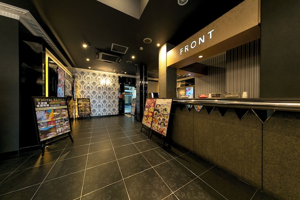 A hotel lobby with a tiled floor, a reception desk labeled "FRONT", and a wall with patterned wallpaper. - Hotel Eldia Modern Kobe (Kobe)