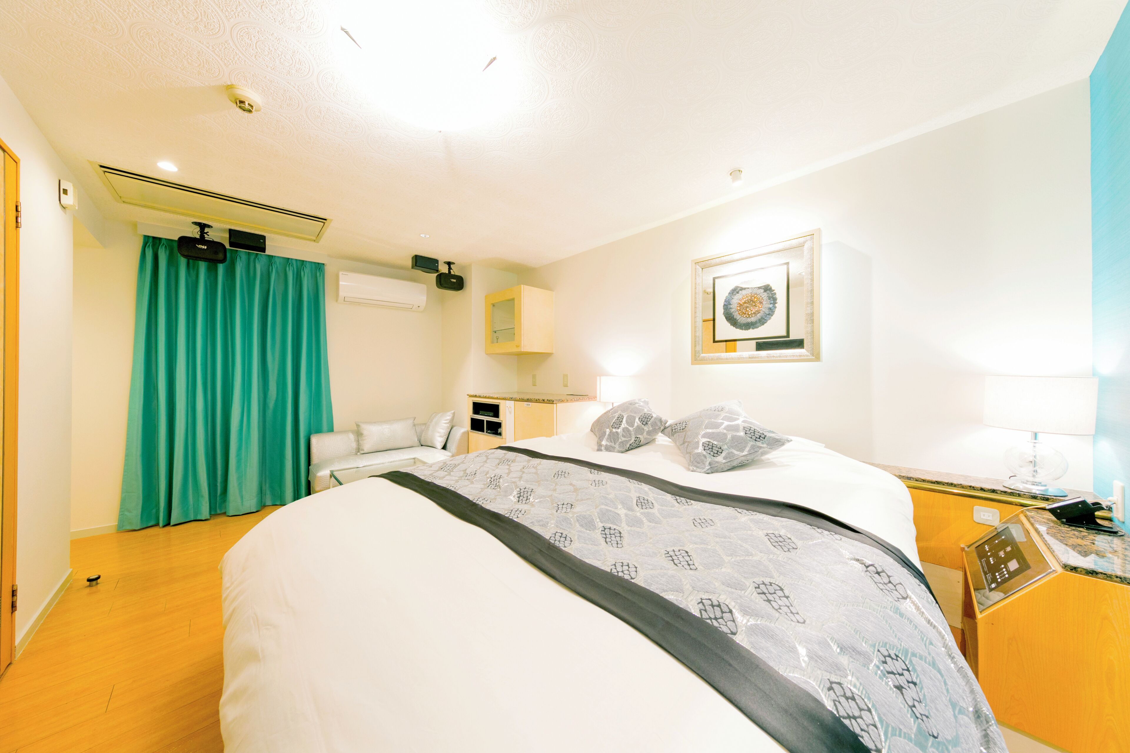Habitación de hotel con cama, escritorio, silla, ventana con cortinas y aire acondicionado instalado en la pared.