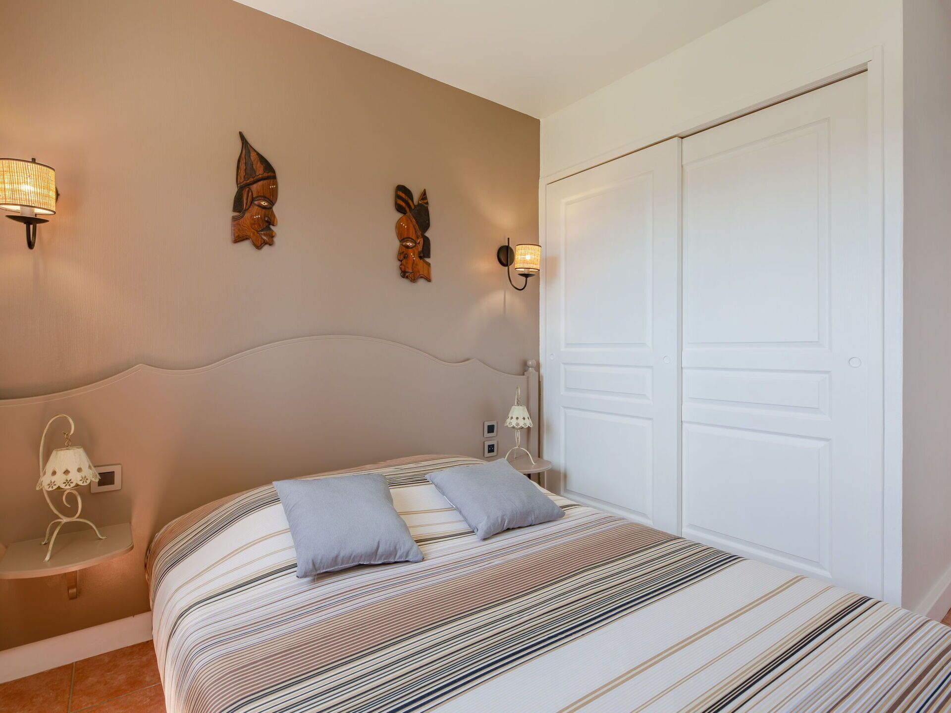 Een slaapkamer met een bed, twee wandlampen en een deur.
