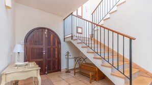 Un escalier avec des marches en bois et des rampes en métal, une porte en bois, une petite table avec une lampe et un radiateur.