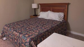 A hotel room with a bed, a bedside table with a lamp, and a small white table. - Peabody 3 Adorable Apartment (Memphis)