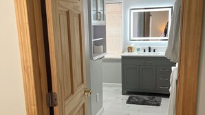 Un baño con suelo de mármol, tocador con espejo y un perchero para toallas.