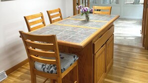 Un comedor con una mesa y sillas de madera, un jarrón con flores e impresiones enmarcadas de motivos botánicos en la pared.