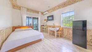 Un dormitorio con cama, escritorio, silla, televisor y refrigerador.
