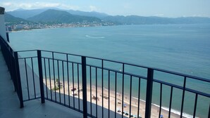 Ein Balkon mit Blick auf einen Strand und eine Stadt im Hintergrund.