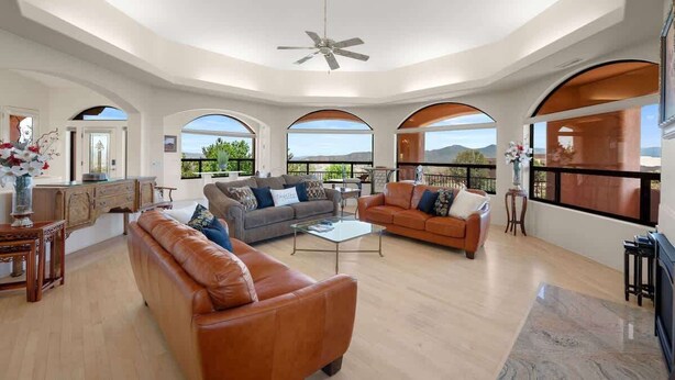 Un salón amplio con techo alto, ventilador de techo y ventanas arqueadas que dan vistas al paisaje.