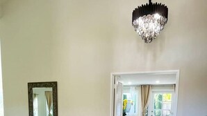 A spacious living area with a glass console table, a chandelier, and a view into a dining area. - Family Paradise near Disneyland w/ Sparkling Pool (Fountain Valley)