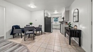 A modern kitchen with white cabinets, a built-in oven, and a dining area with a table and chairs.