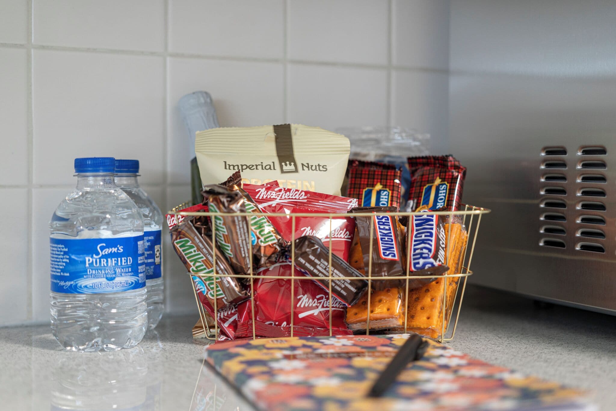 Eine Küchenarbeitsfläche mit einer Wasserflasche, einem Snackkorb und einer Mikrowelle.