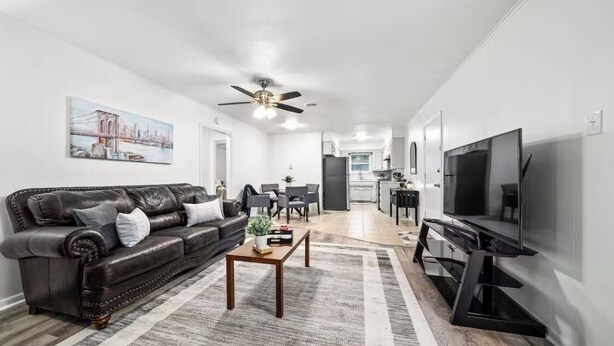 A modern living room with a leather sofa, a coffee table, a TV, and a ceiling fan.