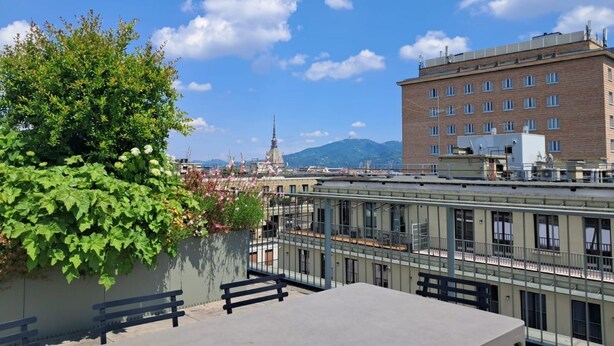 Terraço no telhado com vista para a paisagem urbana, incluindo um edifício com uma torre.