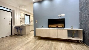 A modern kitchen with a built-in TV, wooden cabinets, and a bar area with stools. - Torino, Tesoriera apartment (Torino)