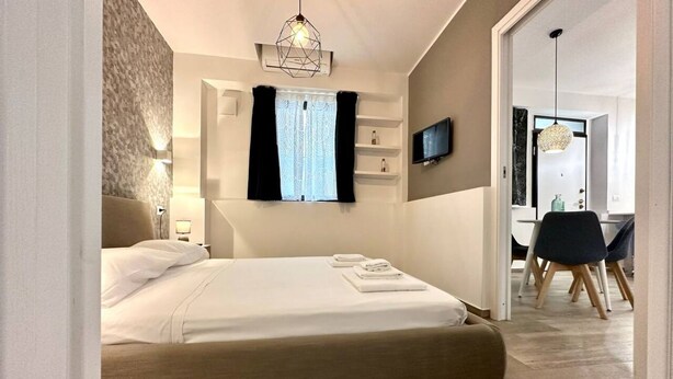 A modern bedroom with a bed, bedside tables, a TV, and a desk with chairs. - Torino, Tesoriera apartment (Torino)