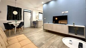A modern living room with a sofa, a dining table with chairs, a kitchen area, and a TV mounted on the wall. - Torino, Tesoriera apartment (Torino)