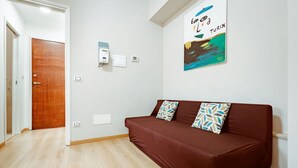 A room with a brown sofa, a wooden door, and a wall-mounted light switch. - Torino Centro, Repubblica Apartment (Torino)