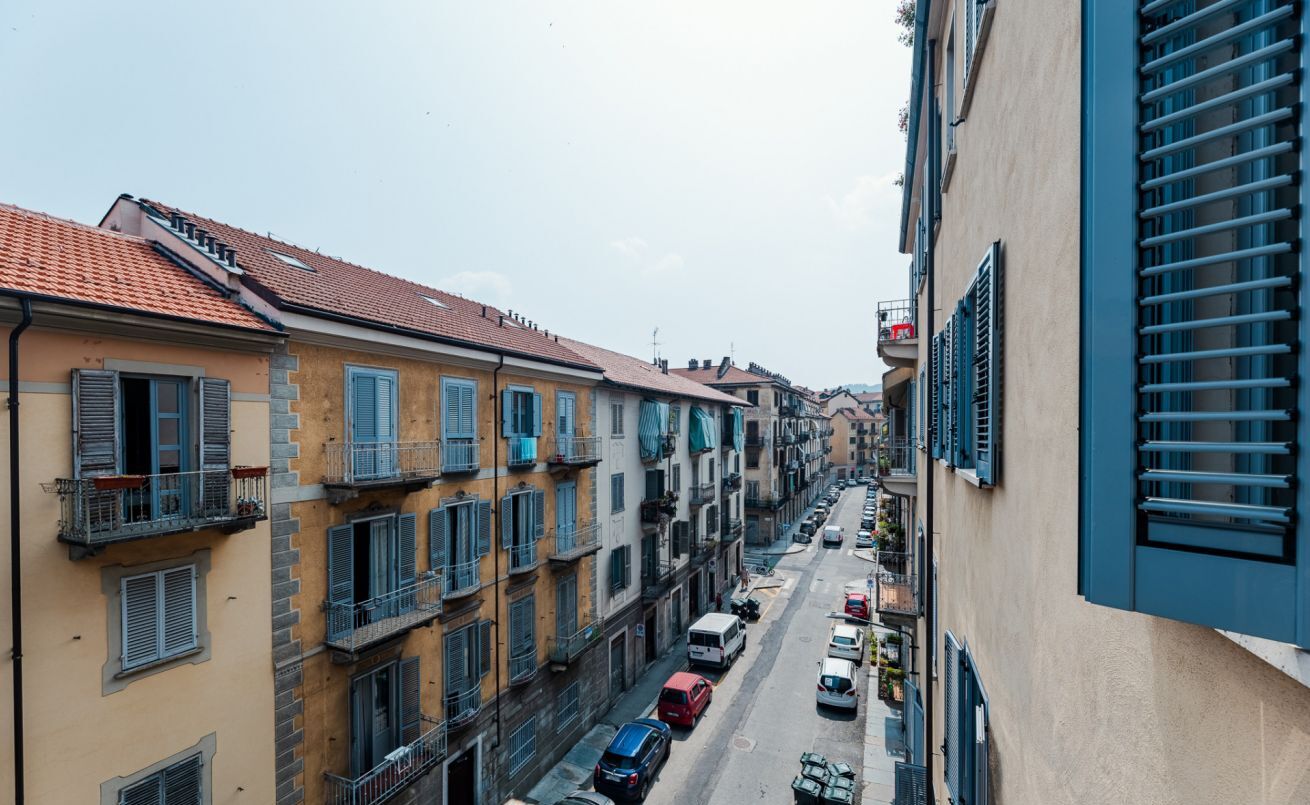 A narrow street lined with multi-story buildings, featuring balconies and a variety of architectural styles.