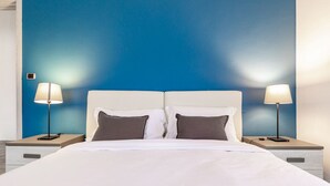 A hotel room with a bed, two bedside tables, and two lamps.