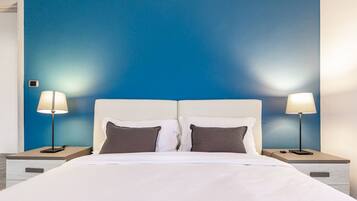 A hotel room with a bed, two bedside tables, and two lamps.