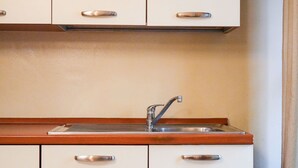Eine Küche mit Spüle aus Edelstahl, einer Holz Arbeitsplatte und weißen Schränken mit silbernen Griffen.