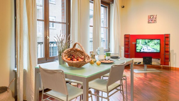 Ein Essbereich mit einem Tisch für zwei Personen, einer Obstschale und einem Fernseher auf einem roten Podest.