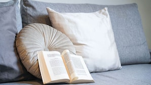 A book open on a grey sofa with a beige pillow and a white pillow. - Torino Centro, Art House Arsenale (Torino)