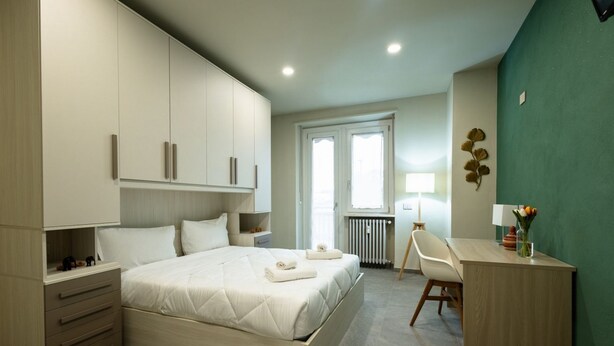 Une chambre à coucher moderne comprenant un lit, une armoire intégrée, des tables de chevet, un bureau et une chaise.