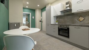 Une cuisine moderne avec des armoires blanches, un four encastré et un coin repas comprenant une table ronde et des chaises.